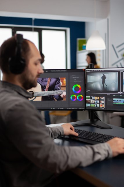 Graphic video production working on pc with two displays editing video and audio footage sitting in creative workplace. Video maker employee processing film montage in digital multimedia company